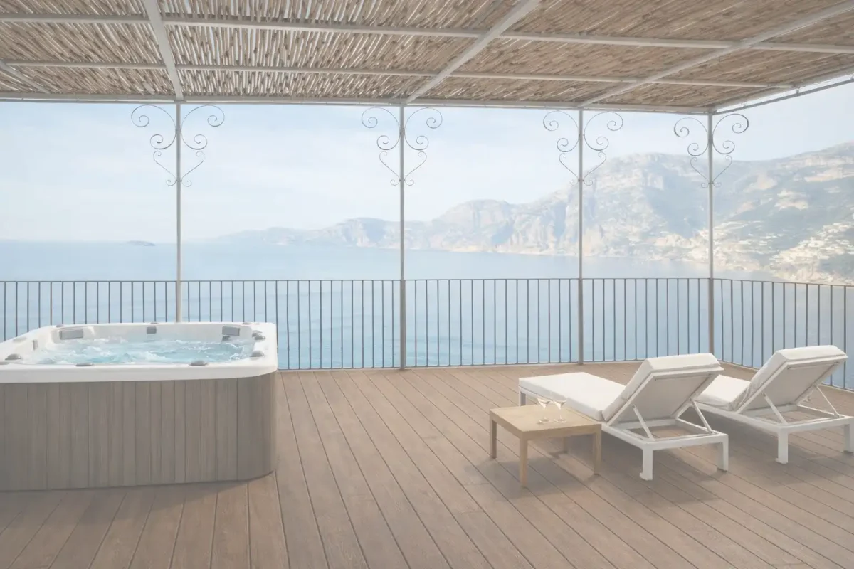 A terrace with a hot tub, sun loungers, and a view of the ocean and mountains.