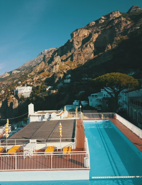 Piscina su un terrazzo con vista sulle montagne rocciose al tramonto.