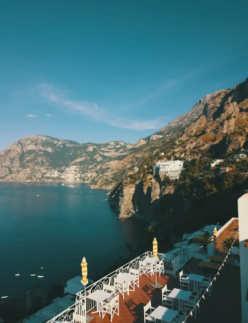 Terrazza panoramica affacciata sulla costa rocciosa con vista sul mare e montagne.