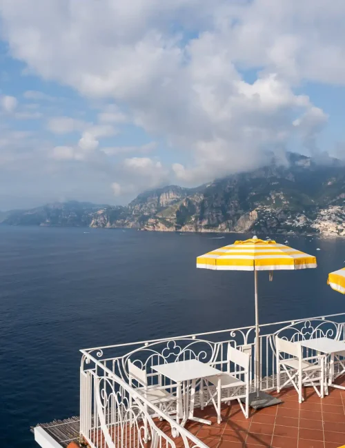 Terrazza con ombrelloni gialli affacciata sul mare lungo la costa.