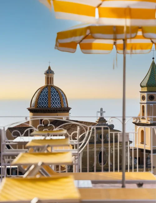 Vista della cupola di una chiesa con ombrelloni a righe gialle in primo piano.